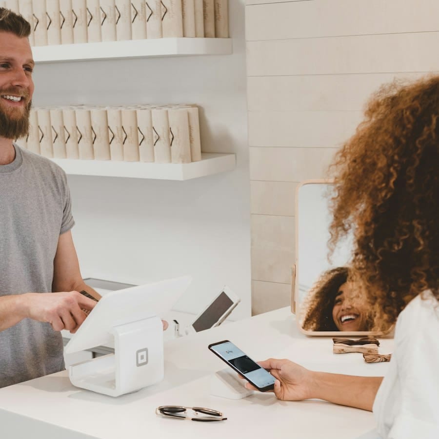 A shop assistant taking a contactless payment at a bright retail counter.